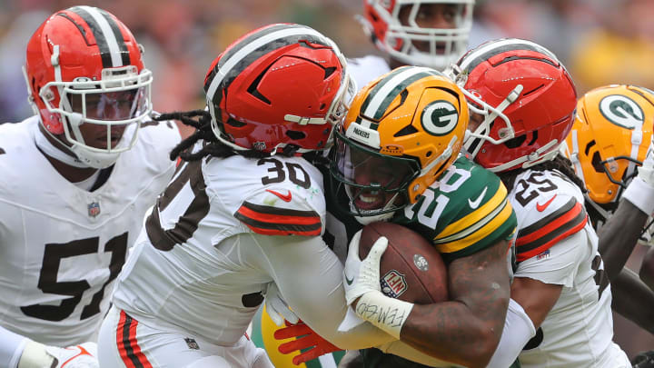 Green Bay Packers running back AJ Dillon (28) is sandwiched between Cleveland Browns linebacker Devin Bush (30) and Cleveland Browns cornerback Kahlef Hailassie (25) during the first half of an NFL preseason football game at Cleveland Browns Stadium, Saturday, Aug. 10, 2024, in Cleveland, Ohio.