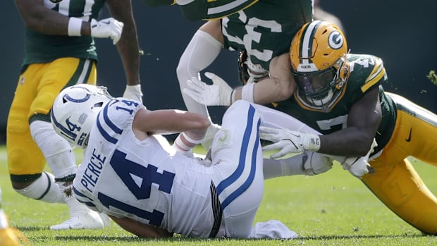 Colts wide receiver Alec Pierce (all-white uniform) gets tackled by multiple Packers defenders (yellow helmet/pants). 