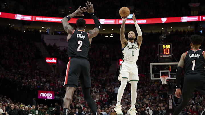 Jan 31, 2024; Portland, Oregon, USA; Milwaukee Bucks guard Damian Lillard (0) shoots a jump shot during the first half against Portland Trail Blazers center Deandre Ayton (2) at Moda Center. Mandatory Credit: Troy Wayrynen-Imagn Images