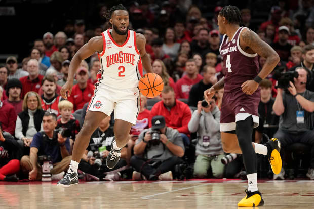 Basketball players dribbles up floor.