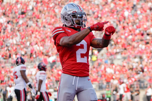 Wide receiver taps wrist in celebration after touchdown.