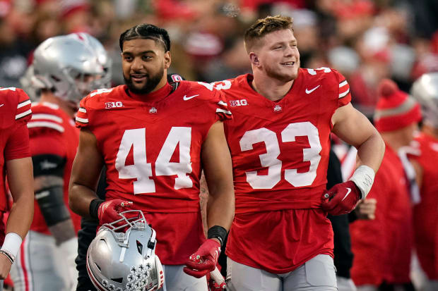 Two players walk on sideline with helmets off.