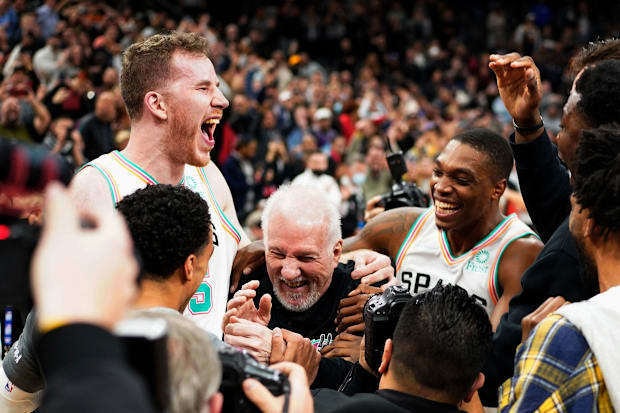 San Antonio Spurs head coach Gregg Popovich is surrounded by players after becoming the winningest coach in NBA history after