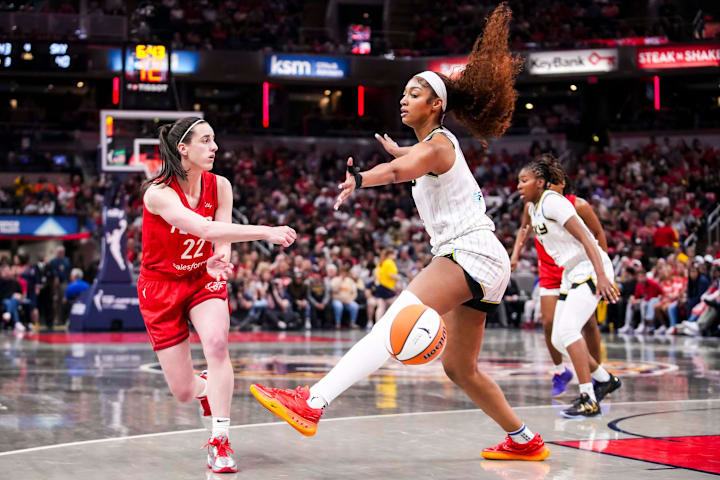 Indiana Fever guard Caitlin Clark passes around Chicago Sky forward Angel Reese.