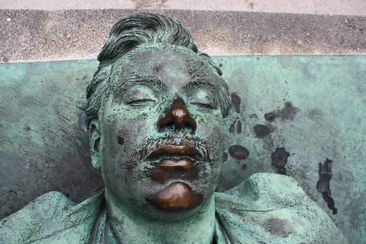 Close-up of Noir's head with a shiny bronze nose and lips while the rest has a heavy verdigris patina