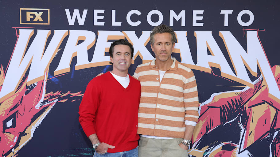 Rob Mac (left) and Ryan Reynolds in front of a poster.
