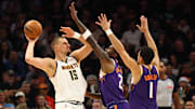 Nov 29, 2025; Phoenix, Arizona, USA; Denver Nuggets center Nikola Jokic (15) controls the ball against Phoenix Suns forward Nigel Hayes-Davis (21) and guard Devin Booker (1) in the first half at the Mortgage Matchup Center. Mandatory Credit: Mark J. Rebilas-Imagn Images