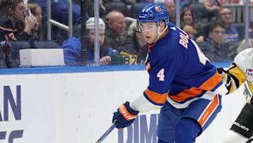 Dec 27, 2023; Elmont, New York, USA; New York Islanders defenseman Samuel Bolduc (4) controls the puck against Pittsburgh Penguins center Jeff Carter (77) during the third period at UBS Arena. Mandatory Credit: Brad Penner-Imagn Images