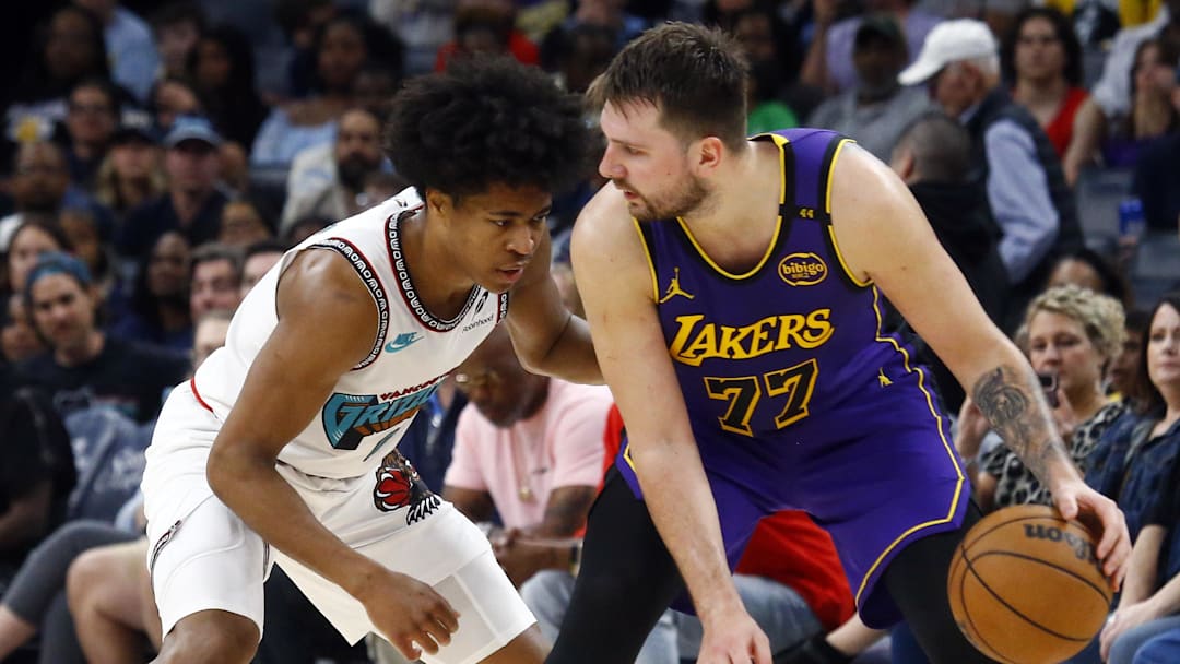 Mar 29, 2025; Memphis, Tennessee, USA; Los Angeles Lakers guard Luka Doncic (77) dribbles as Memphis Grizzlies forward Jaylen Wells (0) defends during the fourth quarter at FedExForum. Mandatory Credit: Petre Thomas-Imagn Images
