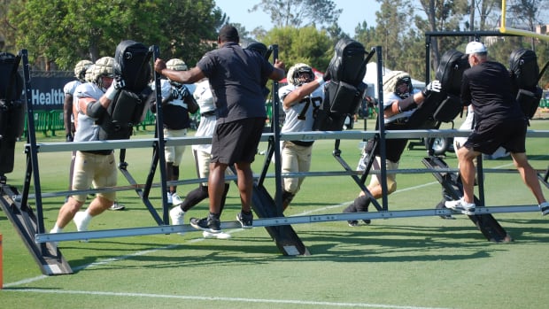 Saints offensive line lifts up the sled with coaches Jahri Evans and John Benton on it.