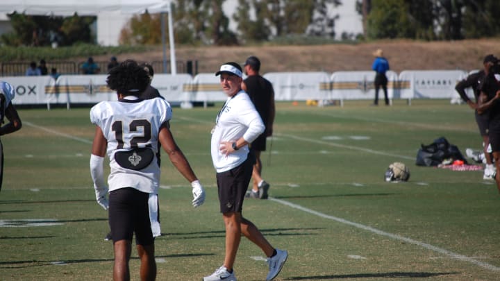 Dennis Allen speaking with Chris Olave during the stretch portion of Saints training camp on Day 13.