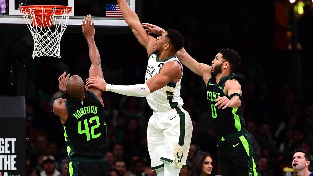 Dec 6, 2024; Boston, Massachusetts, USA;  Milwaukee Bucks forward Giannis Antetokounmpo (34) lays the ball in the basket between Boston Celtics center Al Horford (42) and forward Jayson Tatum (0) during the second half at TD Garden. Mandatory Credit: Bob DeChiara-Imagn Images