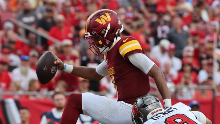 Sep 8, 2024; Tampa, Florida, USA;  Washington Commanders quarterback Jayden Daniels (5) runs past Tampa Bay Buccaneers linebacker SirVocea Dennis (8)  for a touchdown during the second half at Raymond James Stadium. Mandatory Credit: Kim Klement Neitzel-Imagn Images