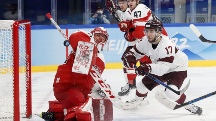 Feb 15, 2022; Beijing, China; Martins Dzierkals of Latvia in action with Sebastian Dahm of Denmark in a men's ice hockey qualification match for the quarterfinal during the Beijing 2022 Olympic Winter Games at Wukesong Sports Centre. Mandatory Credit: David W Cerny/Reuters via USA TODAY Sports