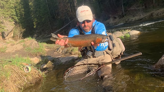 A fly angler holding a big trout caught in a tailwater.
