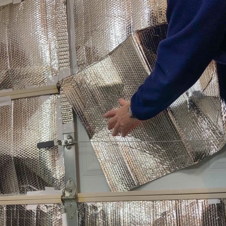 A person insulating their garage with reflective foil.