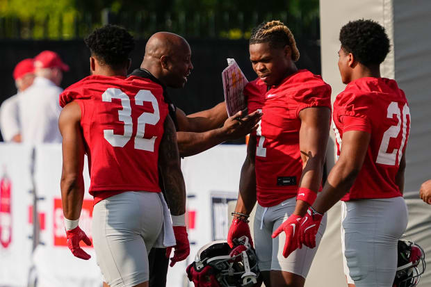 Running backs get instruction from coach.