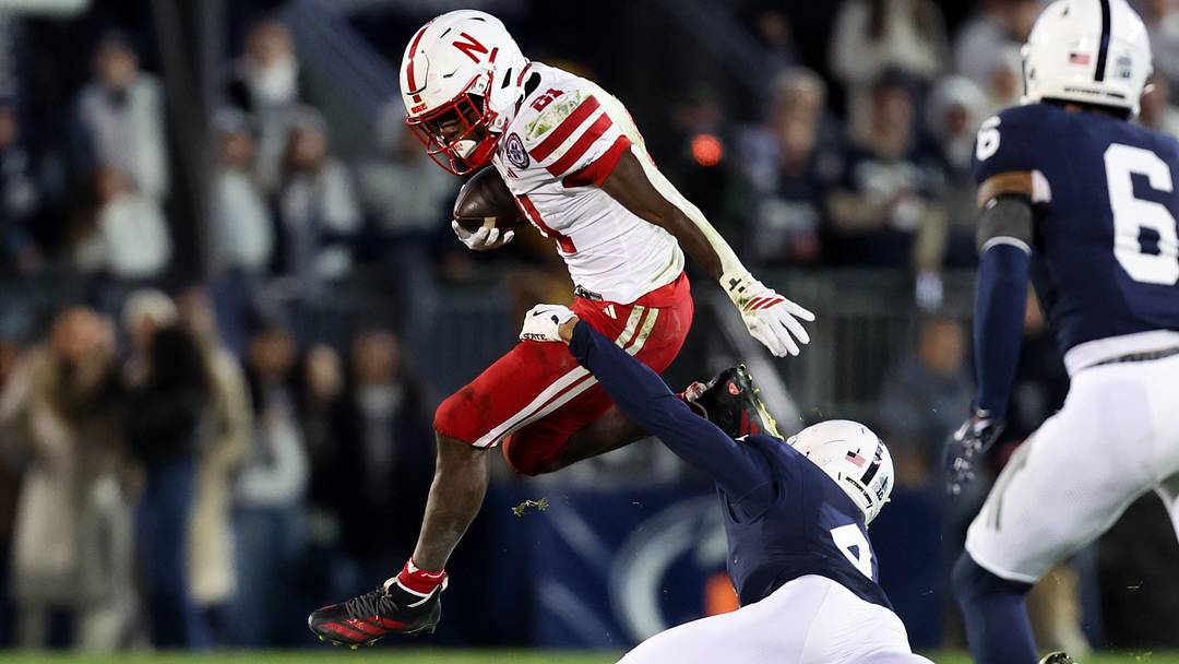 Nebraska running back Emmett Johnson jumps to avoid a tackle from Penn State Nittany Lions cornerback A.J. Harris. Nebraska running back Emmett Johnson jumps to avoid a tackle from Penn State Nittany Lions cornerback A.J. Harris.