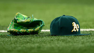 Jul 22, 2025; Arlington, Texas, USA;  Athletics glove and hat on the field before the game against the Texas Rangers at Globe Life Field. Mandatory Credit: Kevin Jairaj-Imagn Images