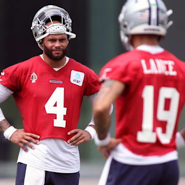 Dallas Cowboys quarterback Dak Prescott and Trey Lance stand on the field during practice.