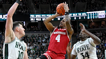 Mar 2, 2025; East Lansing, Michigan, USA;  Wisconsin Badgers guard Kamari McGee (4) tries a shot over Michigan State Spartans center Szymon Zapala (10) during the first half at Jack Breslin Student Events Center. Mandatory Credit: Dale Young-Imagn Images