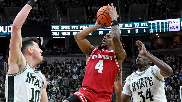 Mar 2, 2025; East Lansing, Michigan, USA;  Wisconsin Badgers guard Kamari McGee (4) tries a shot over Michigan State Spartans center Szymon Zapala (10) during the first half at Jack Breslin Student Events Center. Mandatory Credit: Dale Young-Imagn Images