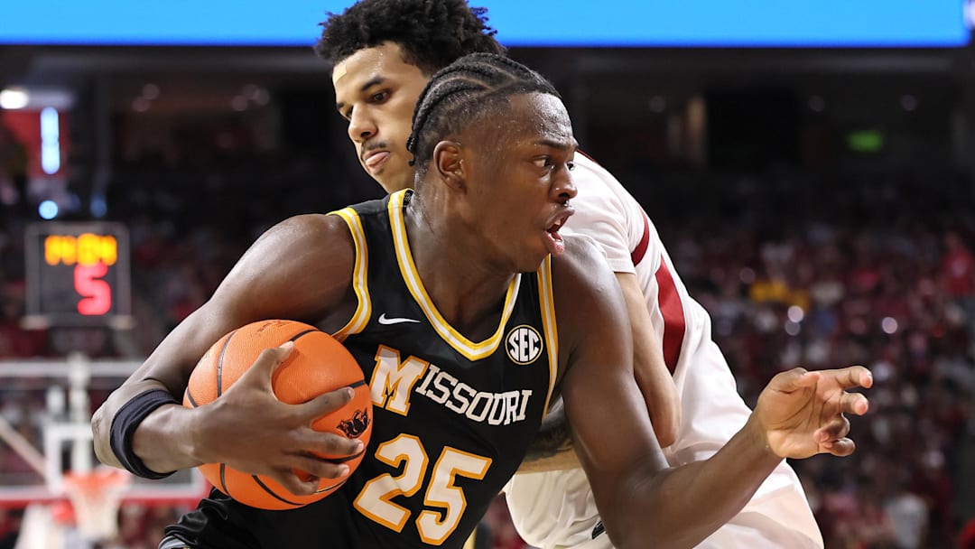 Feb 21, 2026; Fayetteville, Arkansas, USA; Missouri Tigers guard Mark Mitchell (25) drives against Arkansas Razorbacks forward Malique Ewin (12) during the second half at Bud Walton Arena. Arkansas won 94-86. 