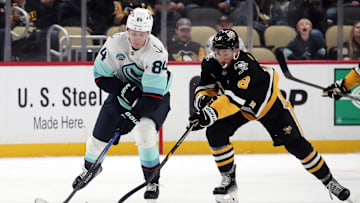 Jan 14, 2025; Pittsburgh, Pennsylvania, USA;  Seattle Kraken right wing Kaapo Kakko (84) skates with the puck as Pittsburgh Penguins left wing Michael Bunting (8) chases during the third period at PPG Paints Arena. Mandatory Credit: Charles LeClaire-Imagn Images