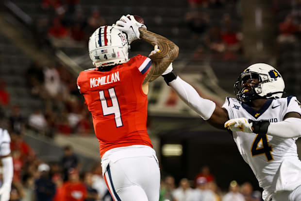 Wildcats WR Tetairoa McMillan catches a long pass while West Virginia Mountaineers linebacker Trey Lathan fails to defend 
