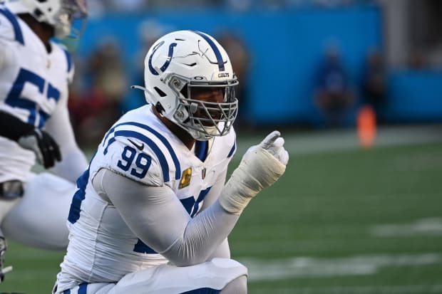 Football player DeForest Buckner reacts after a sack in a white jersey.