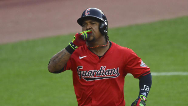 A baseball player wearing a red jersey and navy helmet while running the bases.