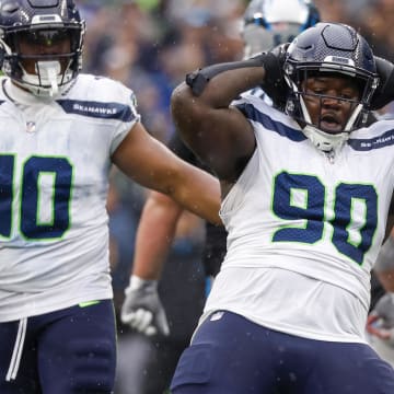 Sep 24, 2023; Seattle, Washington, USA; Seattle Seahawks defensive tackle Jarran Reed (90) celebrates after forcing a turnover on downs by sacking Carolina Panthers quarterback Andy Dalton (14, background) during the fourth quarter at Lumen Field. Mandatory Credit: Joe Nicholson-USA TODAY Sports