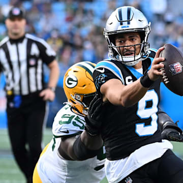Dec 24, 2023; Charlotte, North Carolina, USA; Carolina Panthers quarterback Bryce Young (9) scrambles as Green Bay Packers defensive tackle Devonte Wyatt (95) defends in the fourth quarter at Bank of America Stadium. Mandatory Credit: Bob Donnan-Imagn Images
