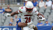 Sep 27, 2025; Pittsburgh, Pennsylvania, USA;  Louisville Cardinals running back Duke Watson (26) carries the ball against linebacker Braylan Lovelace (0) and defensive back Davion Pritchard (23) during the fourth quarter at Acrisure Stadium. Mandatory Credit: Charles LeClaire-Imagn Images