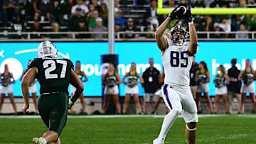 Sep 16, 2023; East Lansing, Michigan, USA;  Washington Huskies tight end Josh Cuevas (85) pulls in a pass against Michigan State Spartans linebacker Cal Haladay (27)   in the third quarter at Spartan Stadium. Mandatory Credit: Dale Young-USA TODAY Sports