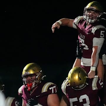 Bishop Watterson's George Pedro (53) lifts Caden Mangini (5) in the air after Mangini scored a touchdown in the first half of the OHSAA Region 11 championship game at White Field on Friday, Nov. 21, 2025 in Newark, Ohio.