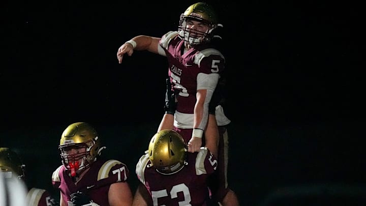Bishop Watterson's George Pedro (53) lifts Caden Mangini (5) in the air after Mangini scored a touchdown in the first half of the OHSAA Region 11 championship game at White Field on Friday, Nov. 21, 2025 in Newark, Ohio.