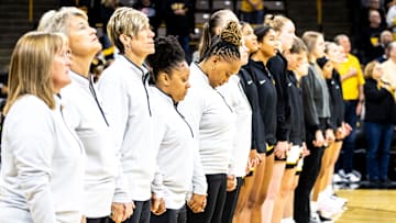 Iowa director of player development Tania Davis holds hands with coaches as the national anthem is performed during a NCAA women's basketball exhibition game between Iowa and Clarke University, Sunday, Oct. 22, 2023, at Carver-Hawkeye Arena in Iowa City.