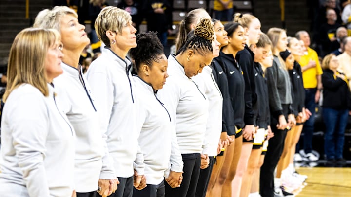 Iowa director of player development Tania Davis holds hands with coaches as the national anthem is performed during a NCAA women's basketball exhibition game between Iowa and Clarke University, Sunday, Oct. 22, 2023, at Carver-Hawkeye Arena in Iowa City.