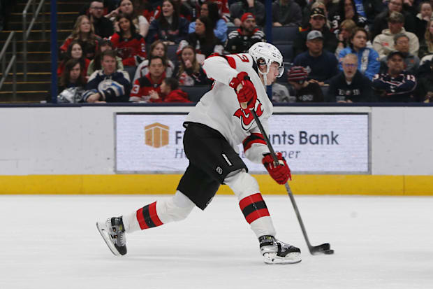 Hockey player in white uniform shoots the puck