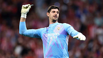 Thibaut Courtois sacando los mecheros que le tiraron los aficionados adversarios a su portería