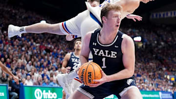 Dec 22, 2023; Lawrence, Kansas, USA; Yale Bulldogs forward Danny Wolf (1) rebounds as Kansas Jayhawks guard Nicolas Timberlake (25) leaps to avoid fouling during the first half at Allen Fieldhouse. Mandatory Credit: Denny Medley-Imagn Images