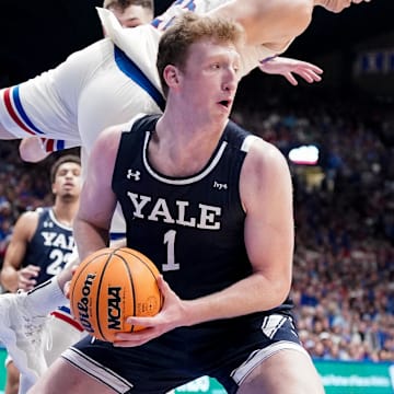 Dec 22, 2023; Lawrence, Kansas, USA; Yale Bulldogs forward Danny Wolf (1) rebounds as Kansas Jayhawks guard Nicolas Timberlake (25) leaps to avoid fouling during the first half at Allen Fieldhouse. Mandatory Credit: Denny Medley-Imagn Images