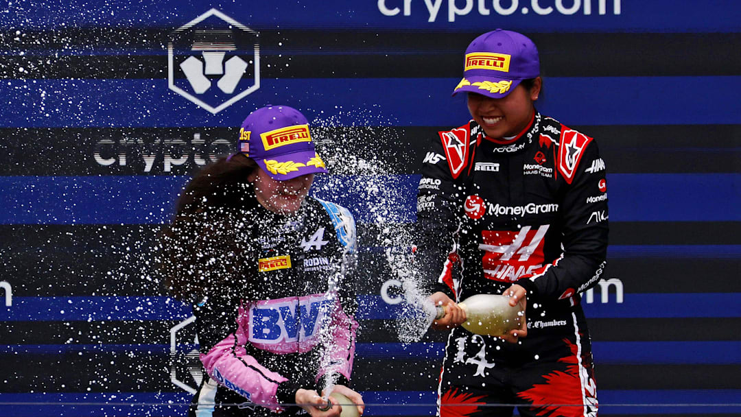 May 4, 2024; Miami Gardens, Florida, USA; F1 Academy driver Chloe Chambers (14) celebrates with F1 Academy driver Abbi Pulling (9) on the podium after the F1 Academy First Race at Miami International Autodrome. Pulling won first place and Chambers won third place. Mandatory Credit: Peter Casey-Imagn Images