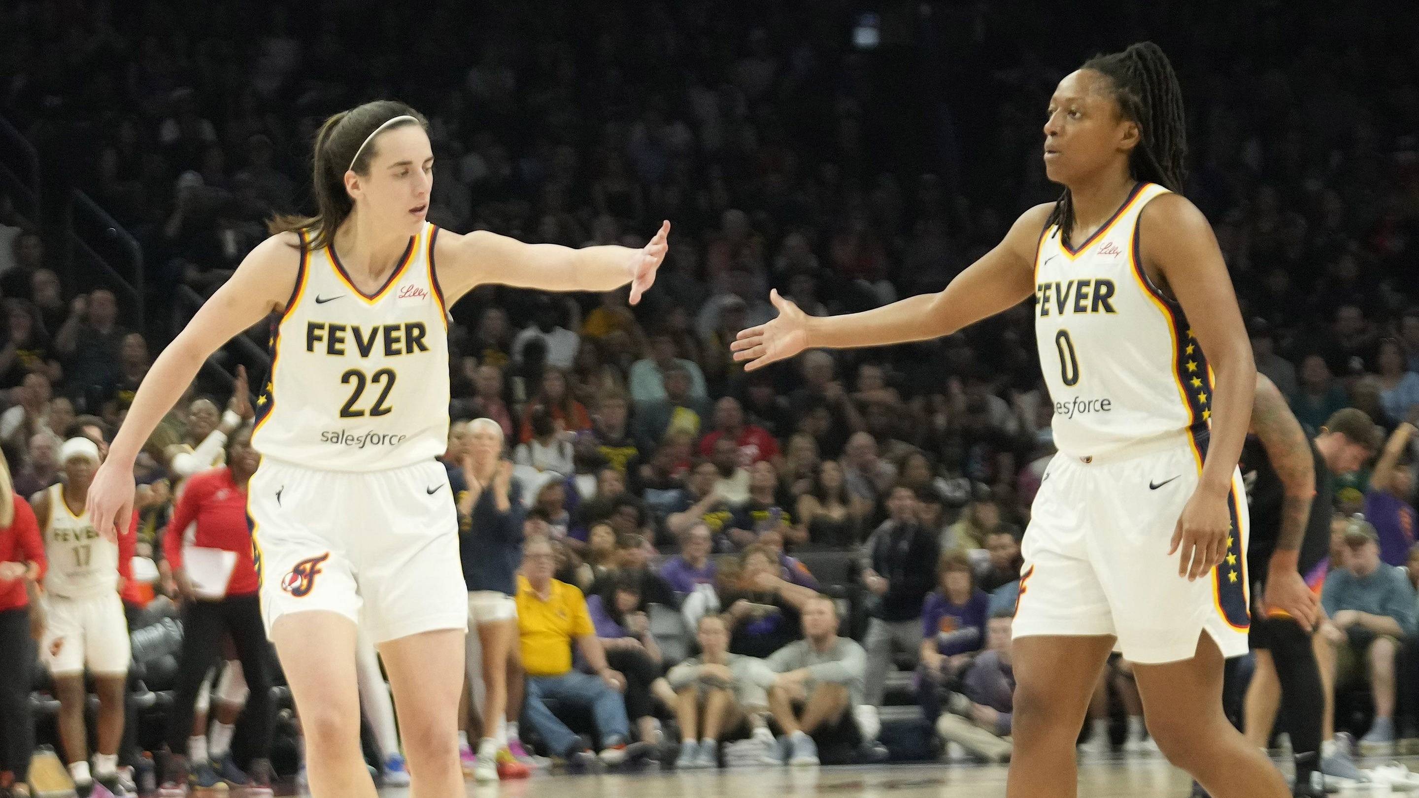 Jun 30, 2024; Phoenix, Ariz., U.S.; Indiana Fever guard Caitlin Clark (22) slaps hands with guard Kelsey Mitchell (0) during the third quarter against the Phoenix Mercury at Footprint Center. Mandatory Credit: Michael Chow-Arizona Republic