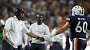 Sep 20, 2025; Charlottesville, Virginia, USA; Virginia Cavaliers head coach Tony Elliott (L) shakes hands with Cavaliers offensive lineman Drake Metcalf (60) after a touchdown against the Stanford Cardinal during the second quarter at Scott Stadium. Mandatory Credit: Geoff Burke-Imagn Images