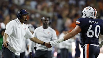 Sep 20, 2025; Charlottesville, Virginia, USA; Virginia Cavaliers head coach Tony Elliott (L) shakes hands with Cavaliers offensive lineman Drake Metcalf (60) after a touchdown against the Stanford Cardinal during the second quarter at Scott Stadium. Mandatory Credit: Geoff Burke-Imagn Images