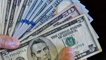 In this photo illustration, a person is seen holding 100, 50...