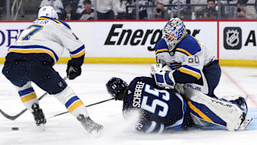 Apr 21, 2025; Winnipeg, Manitoba, CAN; Winnipeg Jets center Mark Scheifele (55) slides into St. Louis Blues goaltender Jordan Binnington (50) after being checked by St. Louis Blues defenseman Cam Fowler (17) in the second period in game two of the first round of the 2025 Stanley Cup Playoffs at Canada Life Centre. Mandatory Credit: James Carey Lauder-Imagn Images