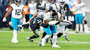 Dec 22, 2024; Paradise, Nevada, USA; Jacksonville Jaguars running back Travis Etienne Jr. (1) is tackled by Las Vegas Raiders safety Thomas Harper (34) and cornerback Decamerion Richardson (25) during the fourth quarter at Allegiant Stadium. Mandatory Credit: Stephen R. Sylvanie-Imagn Images